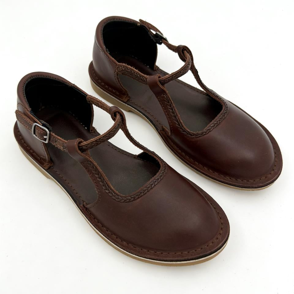 Pair of brown leather shoes with T-straps on a white background